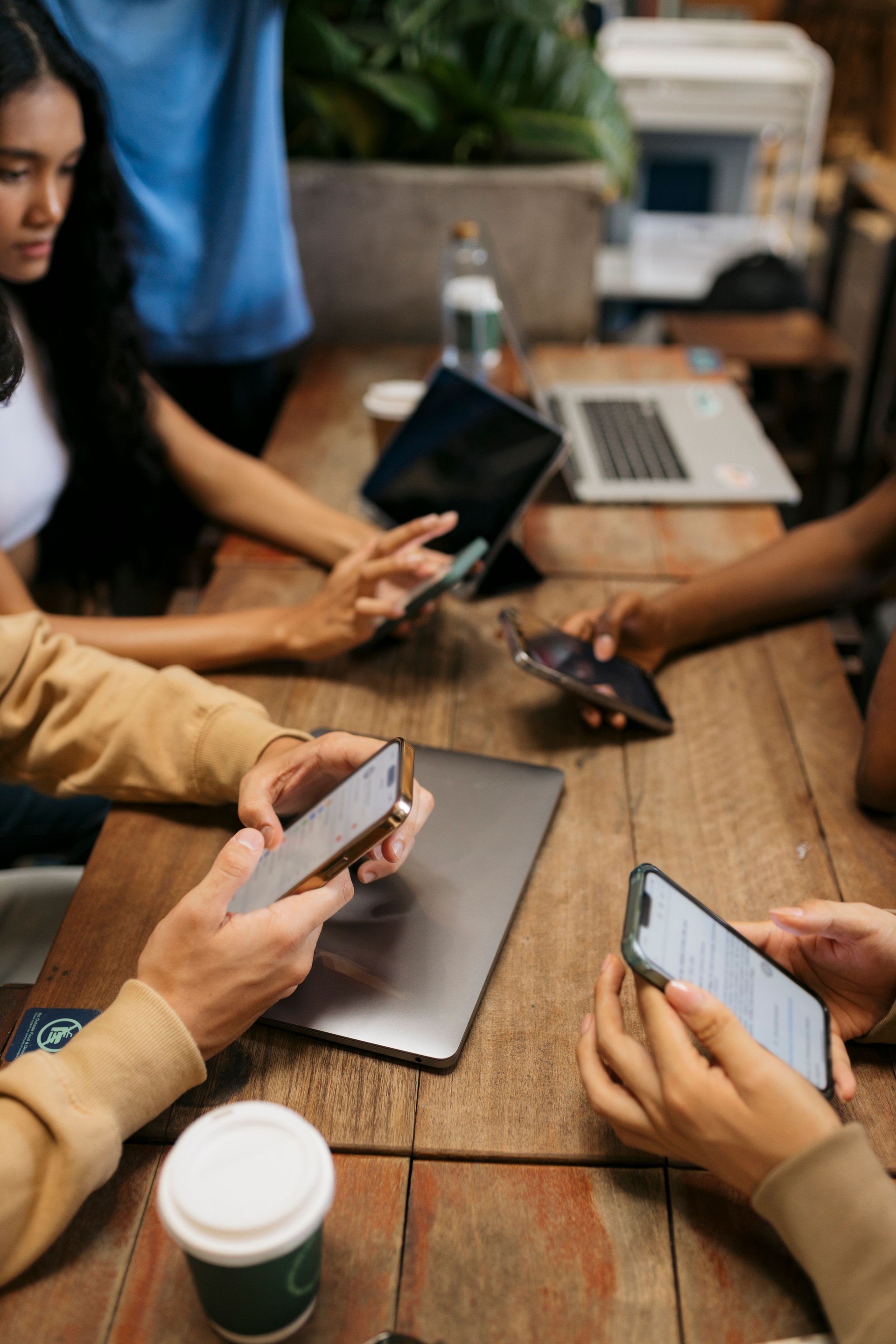 Group of people sitting in cafe together using their phones